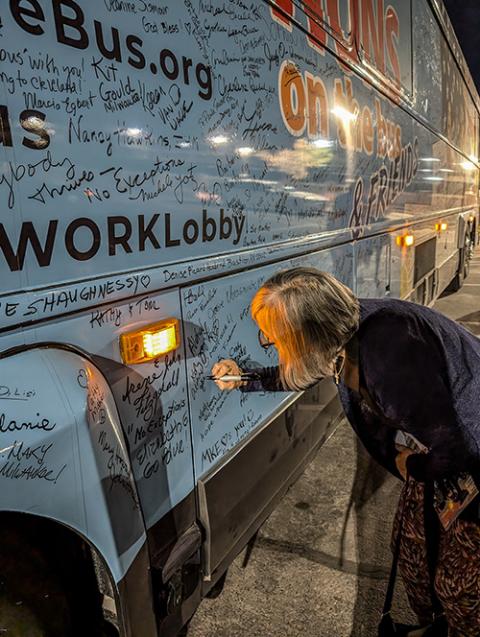 Jackie Barney, visiting Las Vegas from Hawaii, pens "aloha" on the Nuns on the Bus vehicle at the Las Vegas stop Oct. 14. (Alecia Westmorland)