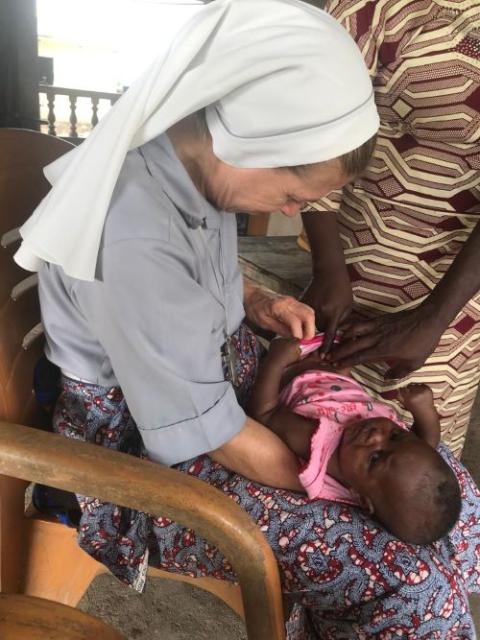 Sr. Monique Bourget examines a baby for malnourishment in Benin.