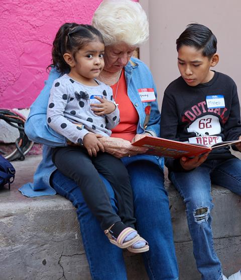A Border Compassion volunteer reads with children residing at the Cobina Posada del Migrante Shelter in Mexicali, Mexico. (Courtesy of Border Compassion)