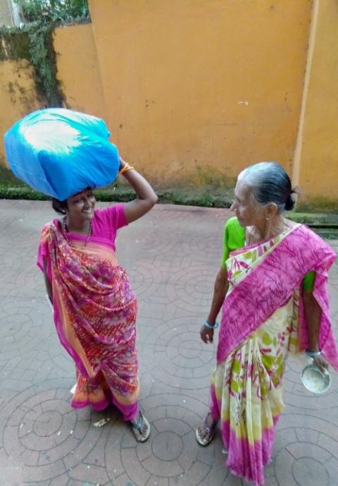 A migrant woman selling waste papers collected from shops stops to converse with another woman in the city center of Panaji, in Goa, western India. (Lissy Maruthanakuzhy)