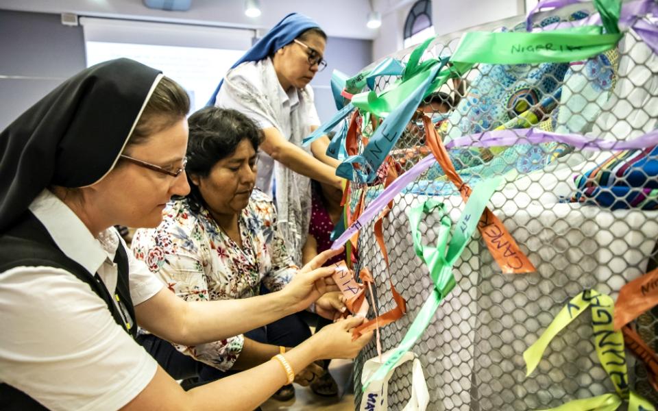 Sisters tie ribbons with the name of their country and a trafficking survivor with whom they have worked with Sept. 27 at the 10th anniversary gathering of Talitha Kum in Rome. (Courtesy of Talitha Kum)