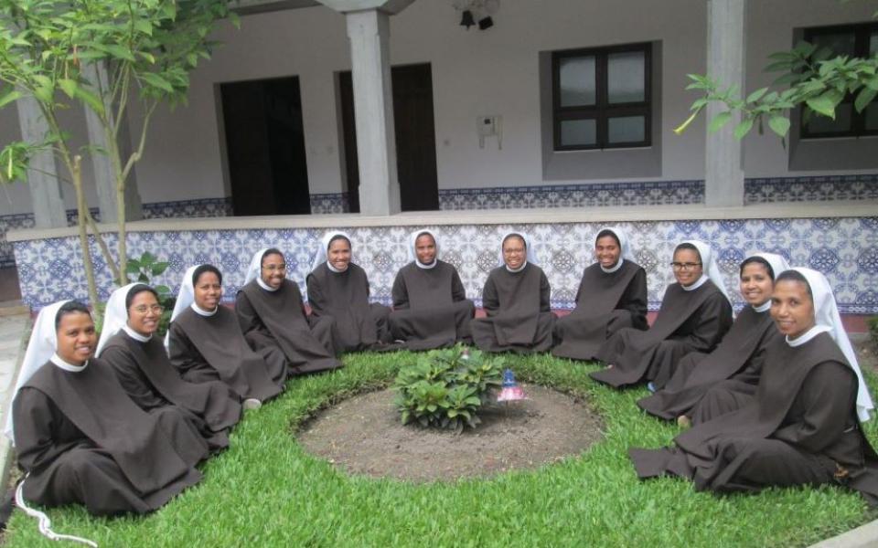 11 Poor Clare sisters sit in semi-circle outside a building.