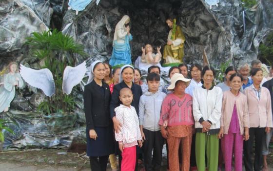 Sr. Anna Vo Thi Ngoi Khen (second from left) and followers of other faiths stand in front of a big crèche on Dec. 12 at her convent in Thua Thien Hue province. (Joachim Pham)