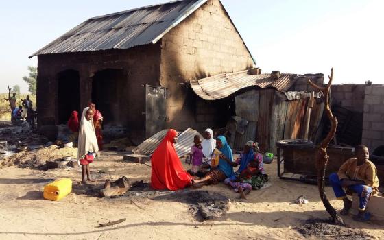 A family is pictured sitting near a damaged home after an attack by suspected members of the Islamist Boko Haram insurgency, Nov. 1, 2018, in Bulabulin, Nigeria. (CNS/Reuters/Kolawole Adewale)