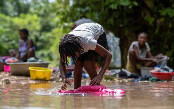 A woman washes clothes Aug. 22 in a river at a makeshift camp in Les Cayes, Haiti, for survivors of the Aug. 14 earthquake.