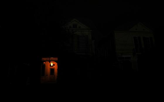 A front porch in New Orleans is lit by a flame on a dark street Aug. 31 in the midst of a power outage caused by Hurricane Ida. (CNS/Reuters/Leah Millis)