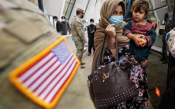 Upon their arrival, Afghan refugees board a bus at Dulles International Airport in Dulles, Virginia, Sept. 1, taking them to a processing center. (CNS/Reuters/Kevin Lamarque)