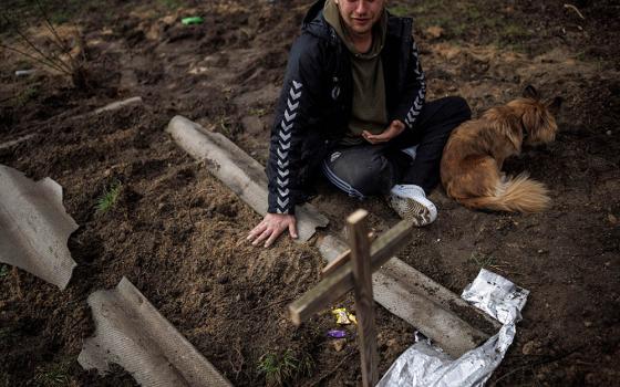 Serhii Lahovskyi, 26, mourns next to the grave of his friend Ihor Lytvynenko after Lytvynenko was found beside a building's basement in Bucha, Uraine, April 6. Residents say Russian soldiers killed Lytvynenko. (CNS/Reuters/Alkis Konstantinidis)