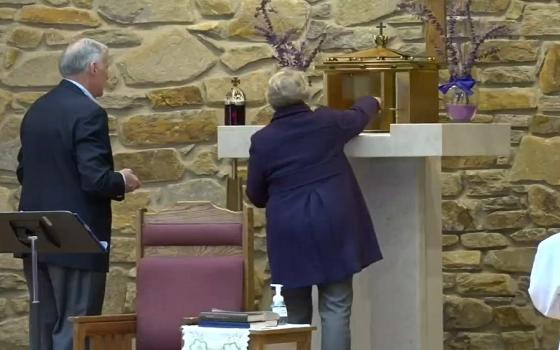 Extraordinary ministers of the Eucharist at St. John the Evangelist Church in Hydes, Maryland, repose the Eucharist in a donated tabernacle during Mass on April 3. (CNS/Catholic Review/Priscila González de Doran)