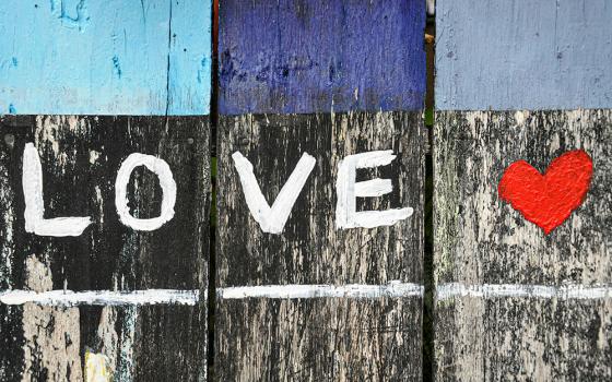 The word LOVE and a red heart painted on a wodden fence (Unsplash/Alex Block)