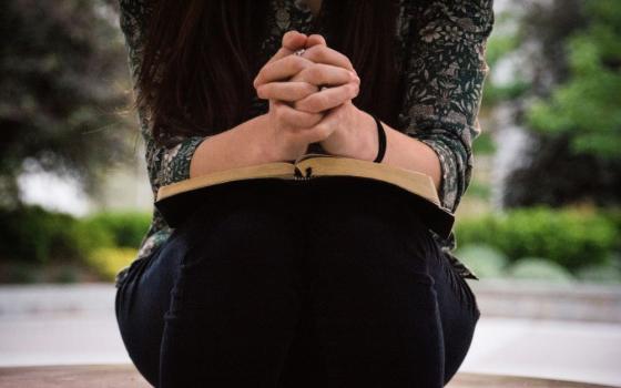 Person with hands folded on book