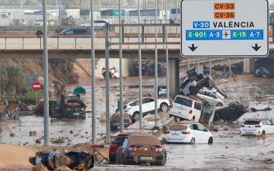 What appears to be an eight-lane highway is covered with mud and abandoned, overturned cars.