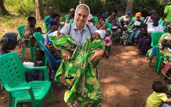 Sr. Monique Bourget holds healthy twins that she accompanied throughout pregnancy and delivery at a gathering of families in Benin. In Benin, she helps coordinate medical missions from Brazil, Canada and Italy. (Courtesy of Sr. Monique Bourget)