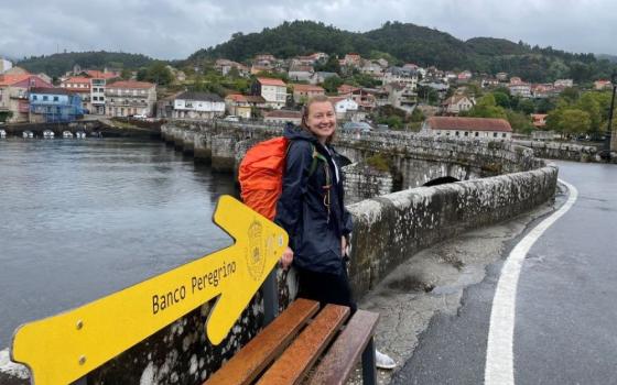 The banco peregrino, a bench along the Camino de Santiago, offers pilgrims a moment of rest. The yellow arrow represents hope and the determination to continue. The author, who lives in Kyiv, Ukraine, spent her annual retreat on a pilgrimage to Santiago de Compostela.