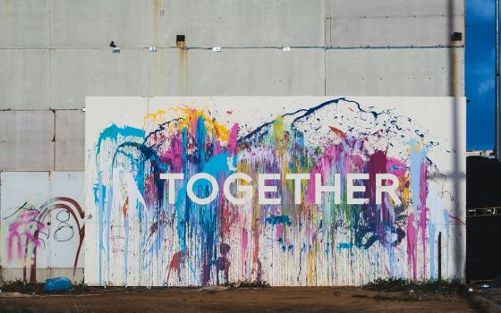 A white sign that says "Together" in white letters on splashes of colors (Unsplash/Nicole Baster)