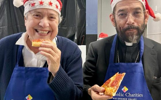 The sister and the bishop smile, wearing aprons and holding slices of pizza.