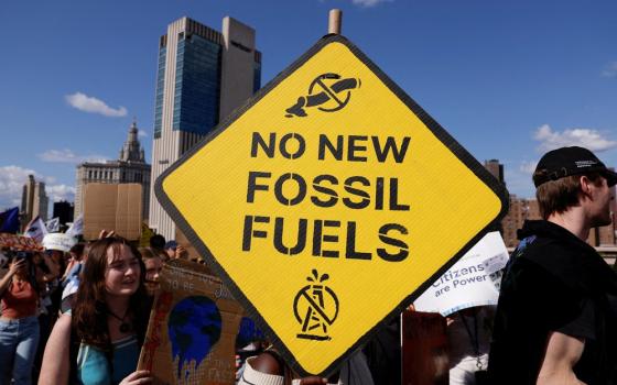 Sign reading "no new fossil fuels" and protestors.