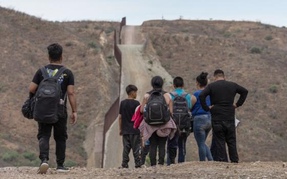 The wall at the U.S.-Mexico border is seen in the background as migrants from South and Central America look to surrender to immigration officials after crossing into the United States from Mexico in Ruby, Ariz., June 24, 2024. (OSV News photo/Adrees Latif, Reuters)