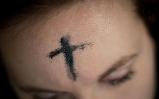 A photo illustration features a close-up of ashes on a woman's forehead. (Unsplash/Ahna Ziegler)