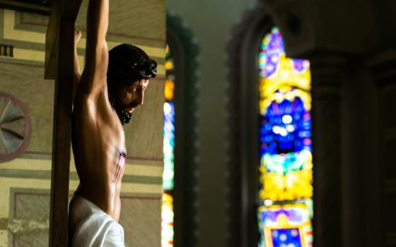 Cropped photo of Jesus Christ on a crucfix with out-of-focus stained glass in the background at at Holy Sacrament Church in Itajai, Brazil. 