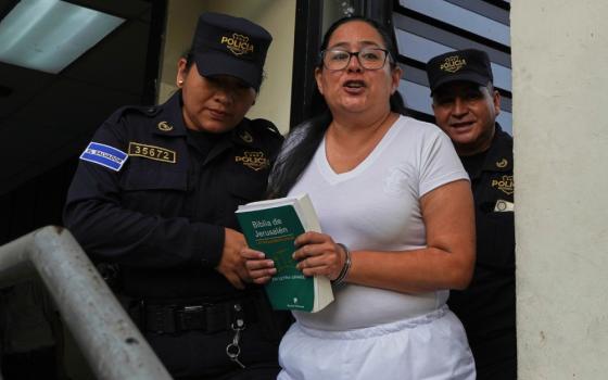 Human rights lawyer Ruth Eleonora Lopez, handcuffed, holds a bible as police escort her out of her court hearing in San Salvador, El Salvador, June 4, 2025. (AP/Salvador Melendez)