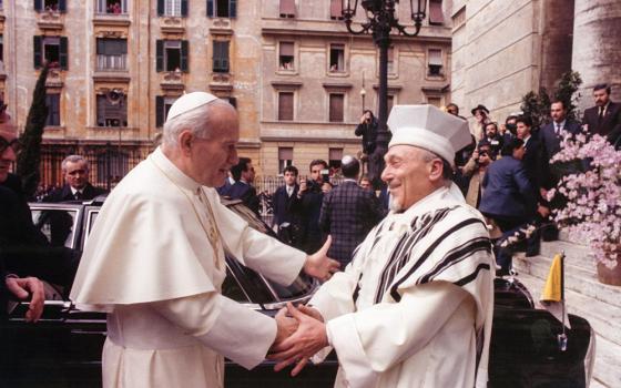 Pope John Paul II greets Rabbi Elio Toaff at Rome’s main synagogue April 13, 1986, in a meeting that marked the first time a pope had entered the Rome synagogue. The 1965 Vatican document Nostra Aetate, which turns 60 this year, paved the way for improved Catholic-Jewish relations. (CNS file/Arturo Mari)