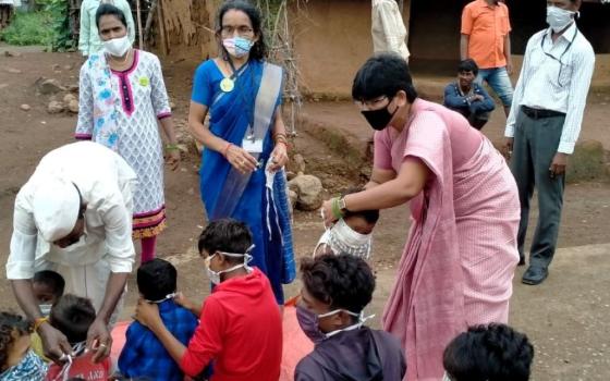 Medical Mission Sr. Seema Bhalrai, coordinator of Child Help Line, ties a mask on a child (Courtesy of Celine Paramundayil)