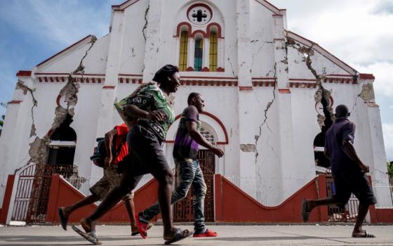 People run past a heavily damaged church in Les Cayes, Haiti, Aug. 18, after a 7.2 magnitude earthquake rocked the area four days earlier. (CNS/Reuters/Ricardo Arduengo)