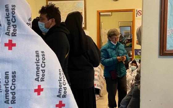 Sr. Judy Bourg (in green coat), a School Sister of Notre Dame, speaks with volunteers and returned migrants on an early morning in October 2021 at the migrant resource center in Agua Prieta, Mexico. (Peter Tran)