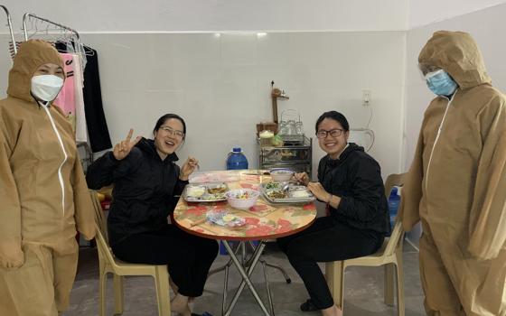 Sr. Mary John Théophan Vénard Doan Thi Chuyen, far left, and another sister in medical gear serve a meal to two nuns with COVID-19 at Ho Ngoc Can Clinic in Xuan Truong district, Nam Dinh province. (Daughters of Our Lady of the Holy Rosary of Bui Chu)