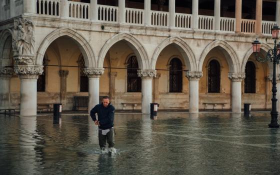 A man wades through knee-high flood waters in St. Mark's Square, Venice, Italy. (Unsplash/Egor Gordeev)