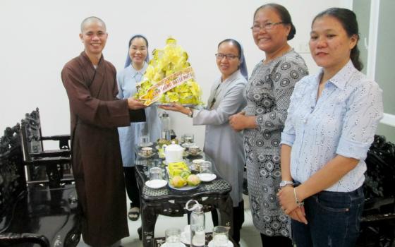 Sr. Anna Nguyen Thi Hien (third from left), another sister and lay volunteers offer flowers to Venerable Thich Tam Quang, a Buddhist monk and clinic director, at Hai Duc Clinic on May 6. (Joachim Pham)